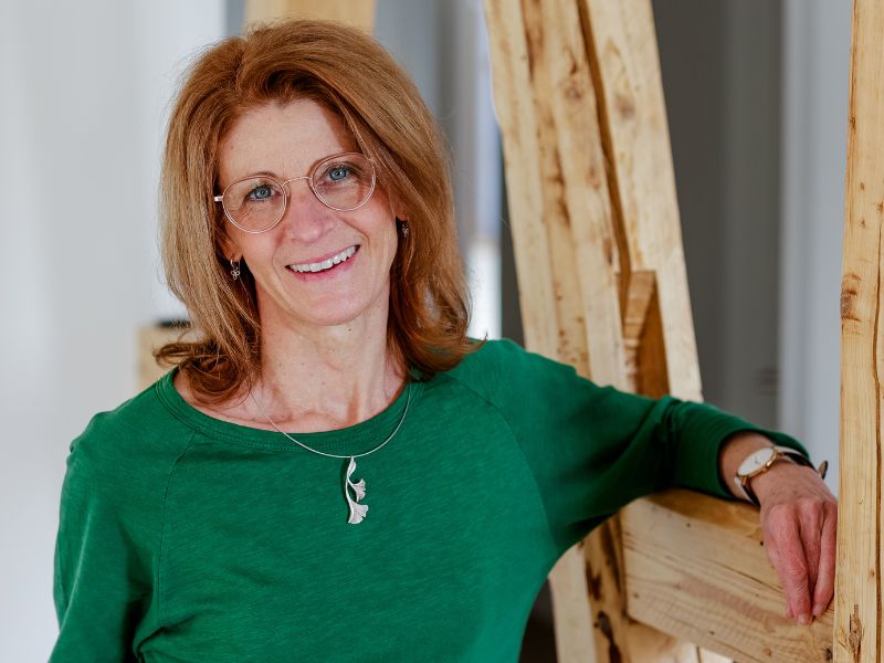 Tina Hirth lehnt an einem Fachwerk-Holzgestell. Sie hat ihre Praxis für Naturheilkunde im Vogelsbergkreis.